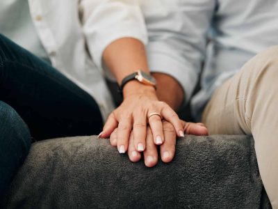 Marriage couple holding hands in counseling for support, mental health and care with zoom on sofa t